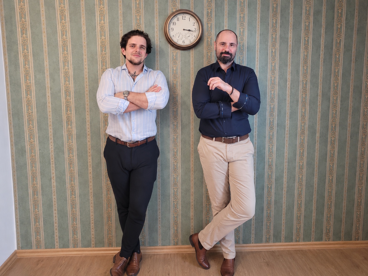 Matei Buliga und Harald Ottawa stehen gemeinsam vor einer grün gemusterten Wand.